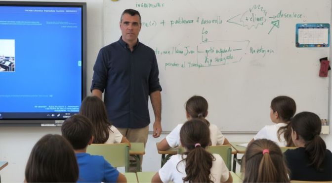 Fernando Armas Pérez imparte un taller de escritura creativa en una pizarra blanca frente a un grupo de alumnos de primaria sentados en sus pupitres.